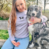 child smiling while wearing a custom embroidered hoodie featuring a hand-drawn pet portrait, the perfect personalised pet gift