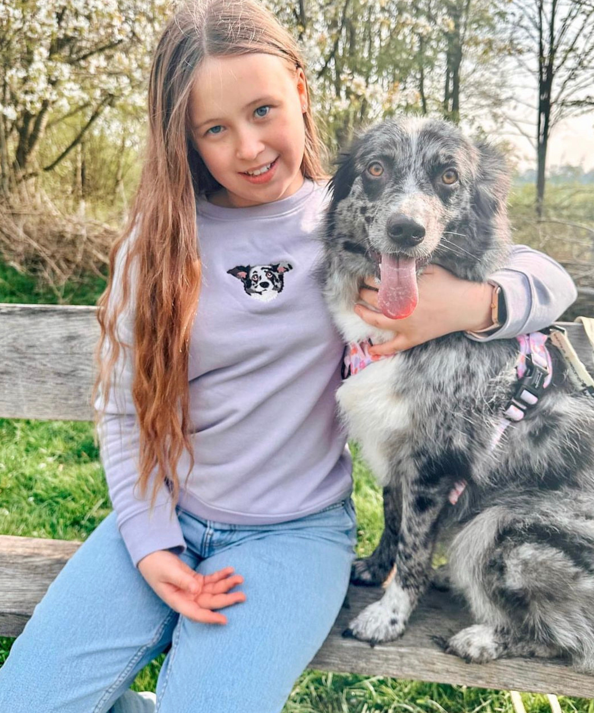 child smiling while wearing a custom embroidered hoodie featuring a hand-drawn pet portrait, the perfect personalised pet gift