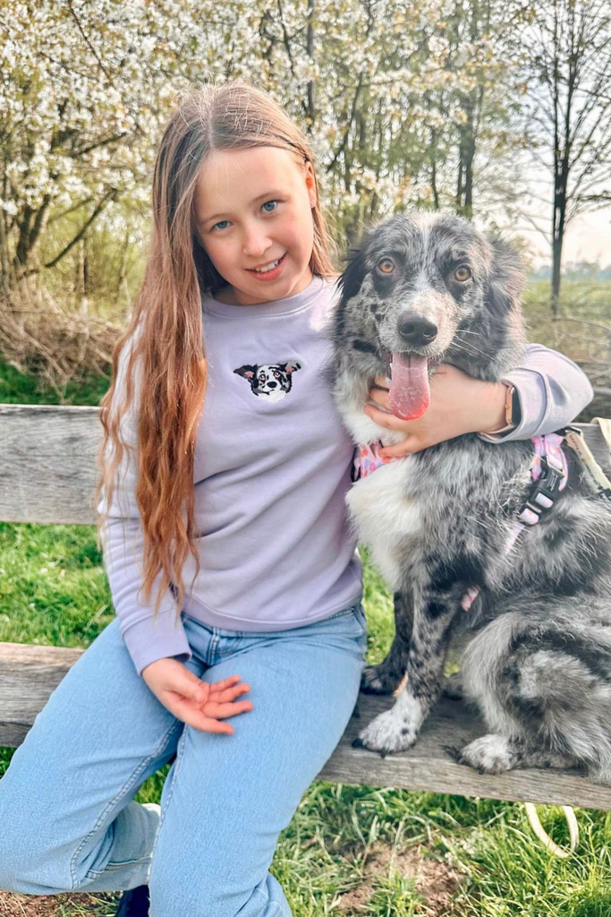 child smiling while wearing a custom embroidered hoodie featuring a hand-drawn pet portrait, the perfect personalised pet gift