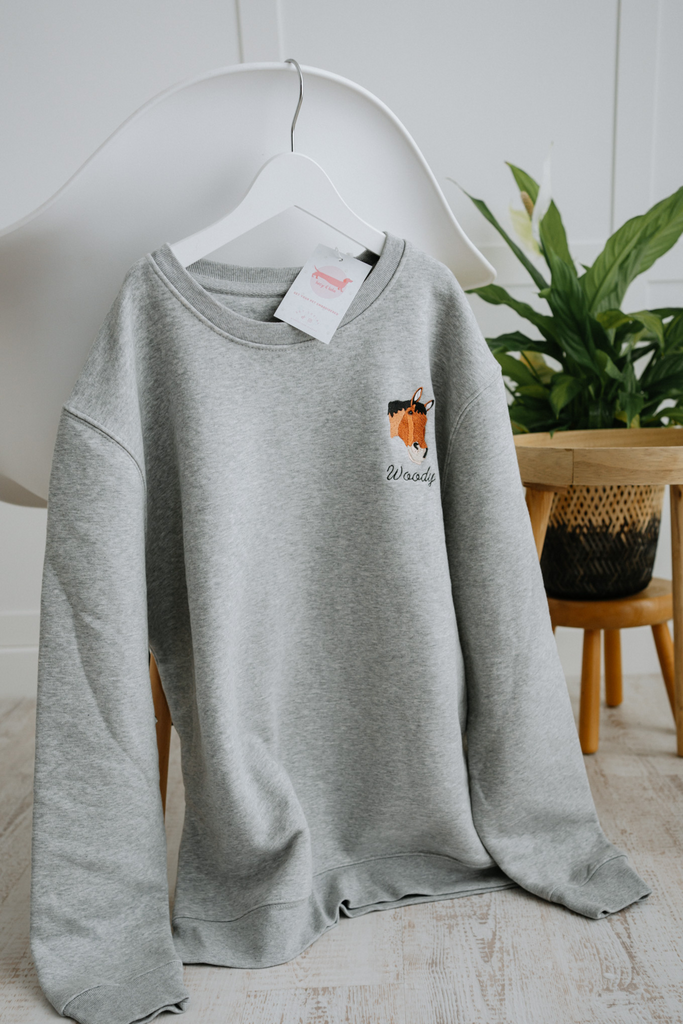 Custom embroidered sweatshirt featuring a hand-drawn pet portrait on organic cotton fabric.
